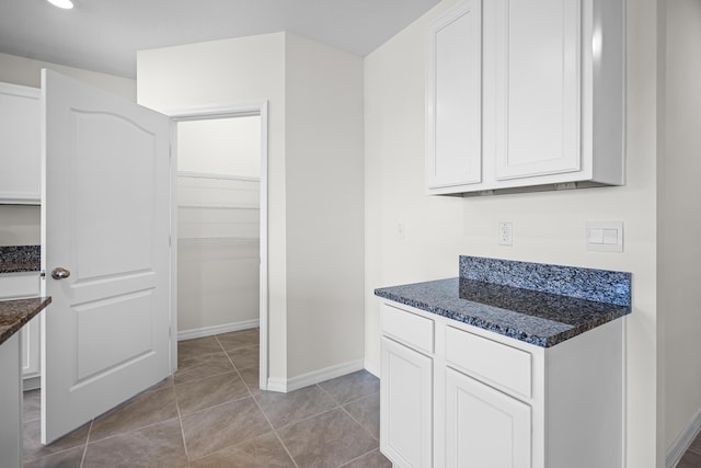 kitchen featuring white cabinetry, dark stone countertops, and light tile patterned flooring