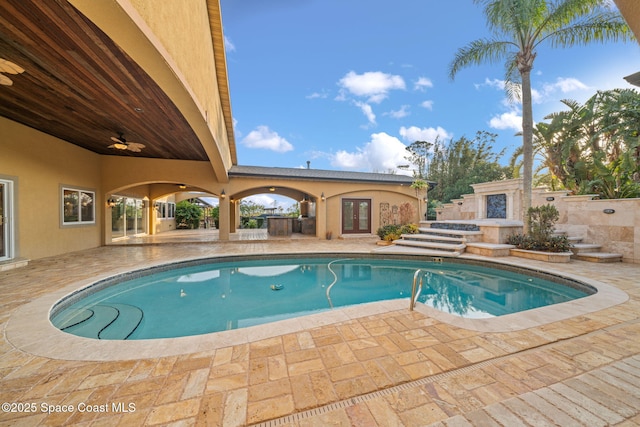 view of swimming pool with ceiling fan, an outdoor fireplace, and a patio area