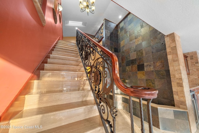 stairway with an inviting chandelier and tile walls