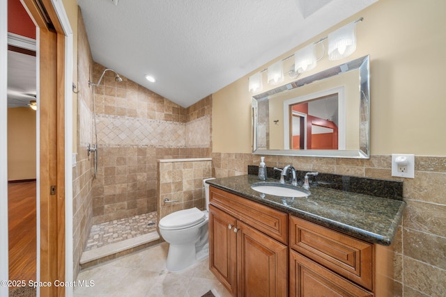 bathroom featuring tile walls, vanity, a textured ceiling, and tiled shower