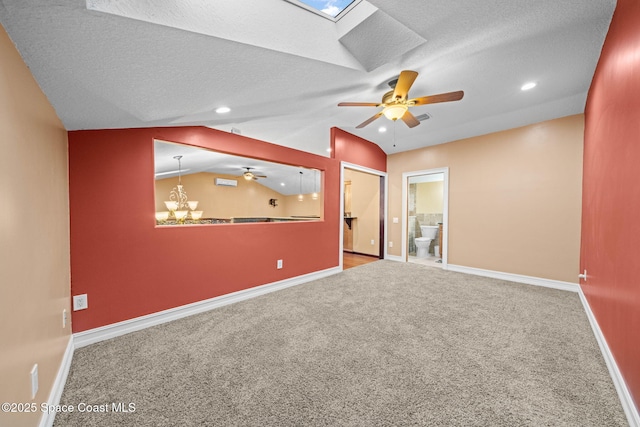 carpeted spare room with ceiling fan with notable chandelier, lofted ceiling with skylight, and a textured ceiling