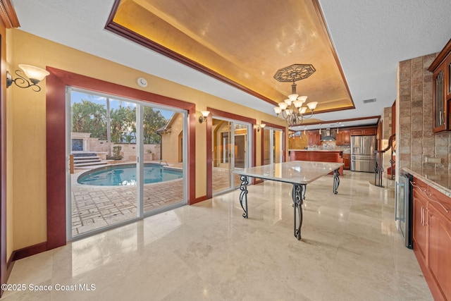 recreation room with a raised ceiling, beverage cooler, and an inviting chandelier