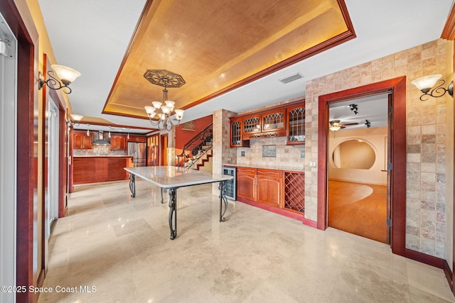 recreation room featuring wine cooler, a raised ceiling, light tile patterned floors, and a notable chandelier