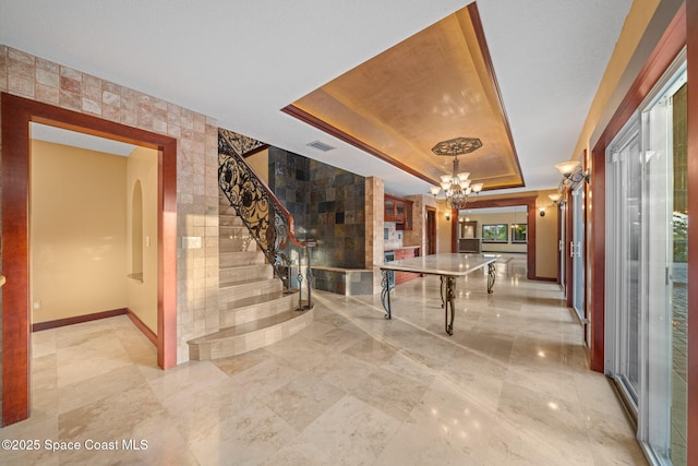 game room featuring an inviting chandelier and a raised ceiling