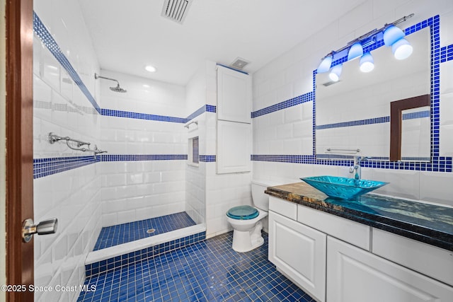 bathroom featuring tile walls, vanity, toilet, and tiled shower