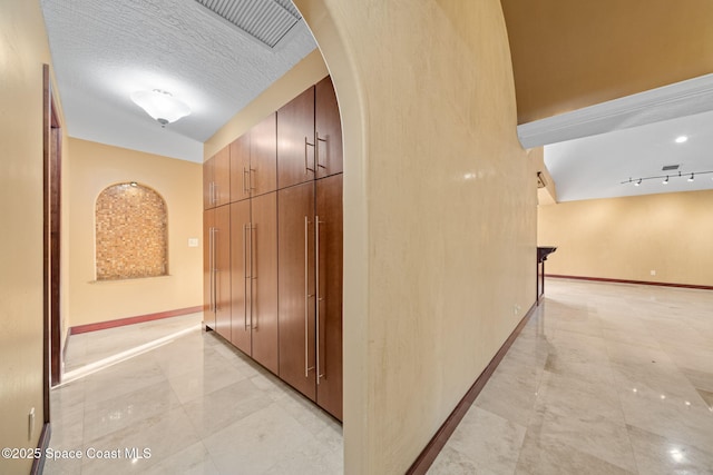 hallway featuring track lighting and a textured ceiling