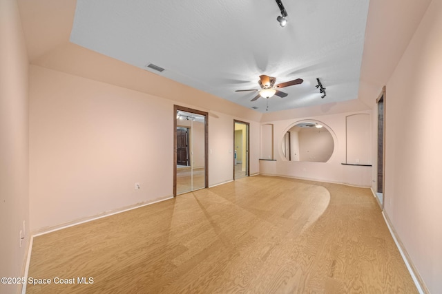 spare room featuring light hardwood / wood-style flooring, ceiling fan, and track lighting