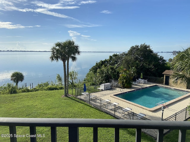 view of pool featuring a water view, a patio, and a lawn