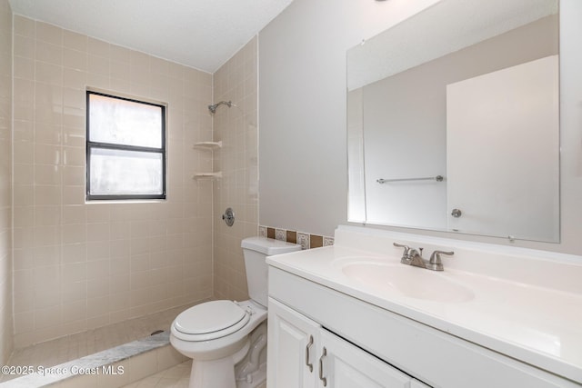 bathroom featuring vanity, tiled shower, and toilet