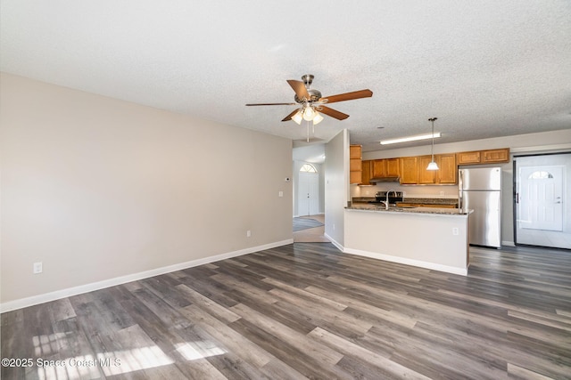 kitchen with a textured ceiling, dark hardwood / wood-style floors, stainless steel fridge, pendant lighting, and ceiling fan