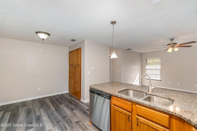 kitchen with sink, dark wood-type flooring, hanging light fixtures, light stone counters, and stainless steel dishwasher