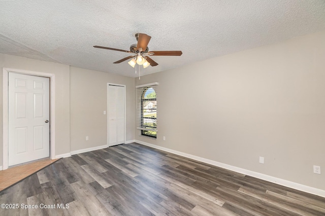 empty room featuring ceiling fan, dark hardwood / wood-style floors, and a textured ceiling