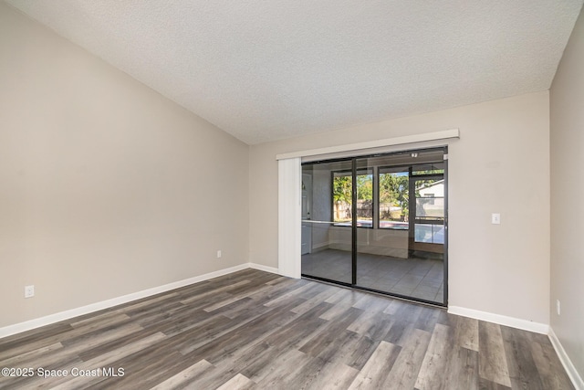 spare room featuring vaulted ceiling, hardwood / wood-style floors, and a textured ceiling