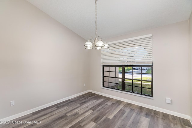 spare room featuring hardwood / wood-style flooring, vaulted ceiling, a textured ceiling, and a chandelier