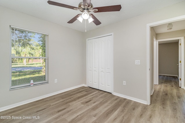 unfurnished bedroom with ceiling fan, a closet, and light wood-type flooring