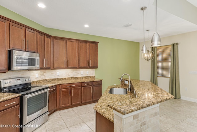 kitchen with sink, stainless steel appliances, light stone countertops, a kitchen island with sink, and backsplash