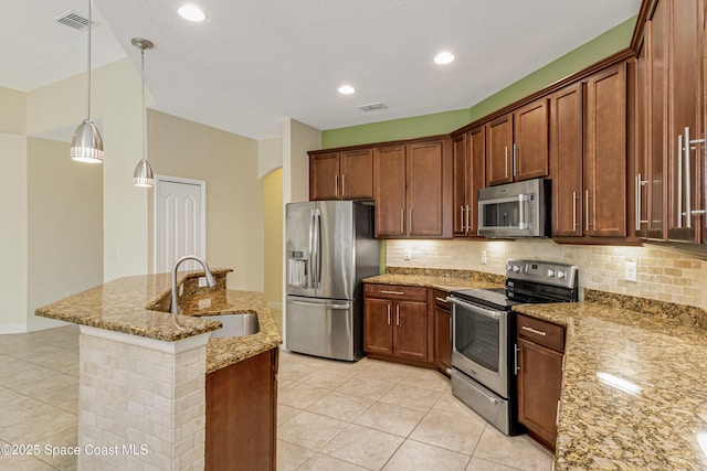 kitchen featuring appliances with stainless steel finishes, sink, pendant lighting, and light stone counters