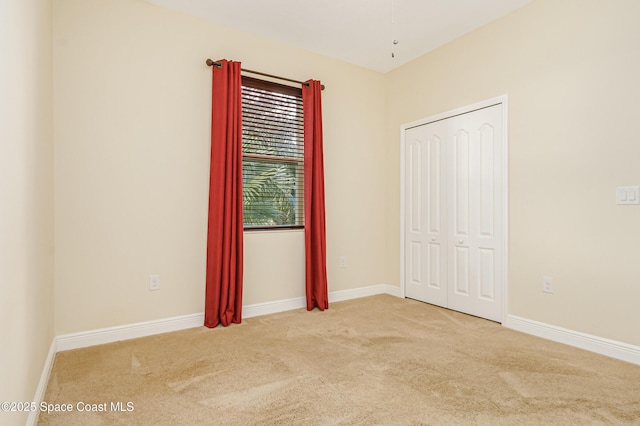 unfurnished bedroom featuring light colored carpet and a closet