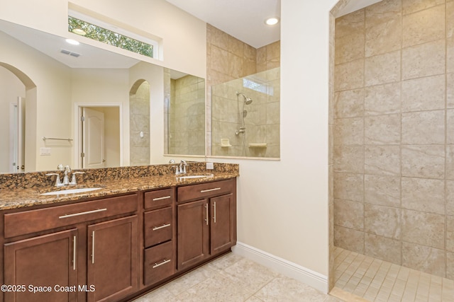 bathroom with vanity, tiled shower, and tile patterned floors