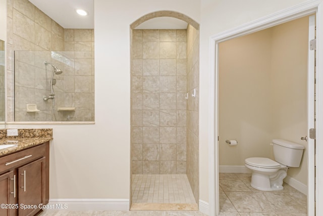 bathroom with tiled shower, vanity, toilet, and tile patterned flooring