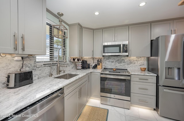 kitchen with sink, gray cabinetry, stainless steel appliances, light stone counters, and tasteful backsplash