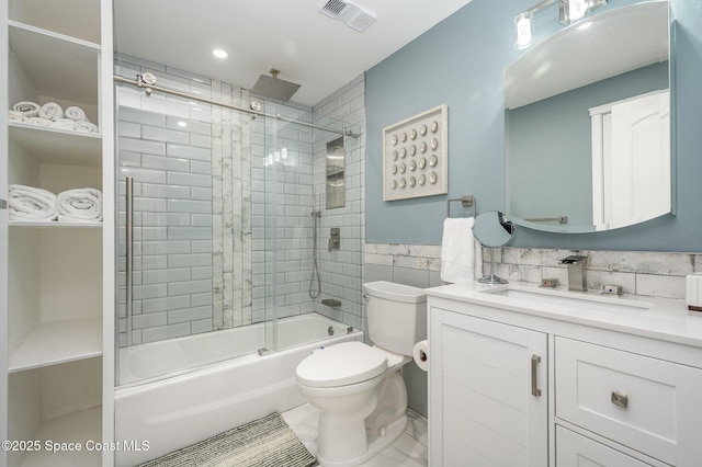 full bathroom featuring shower / bath combination with glass door, vanity, toilet, and tile walls