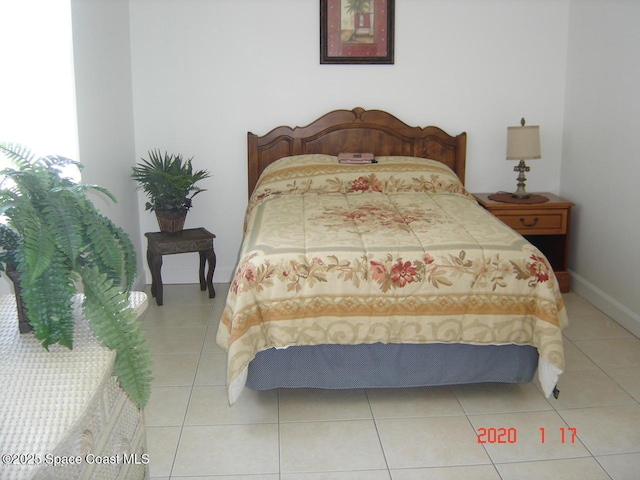 bedroom with light tile patterned floors and baseboards