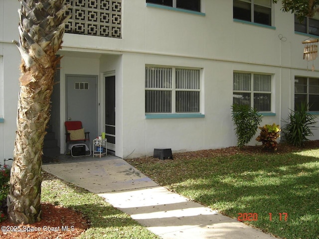 doorway to property with visible vents, a yard, and stucco siding