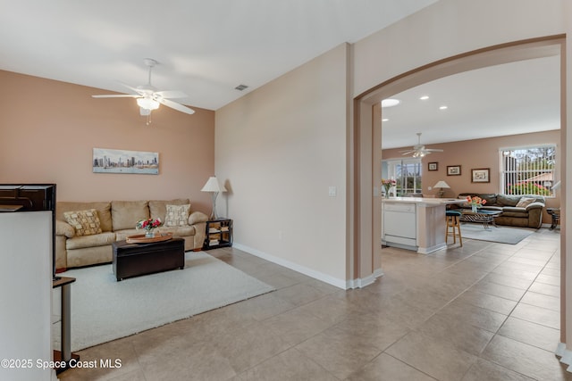 living room with a wealth of natural light, ceiling fan, and light tile patterned floors