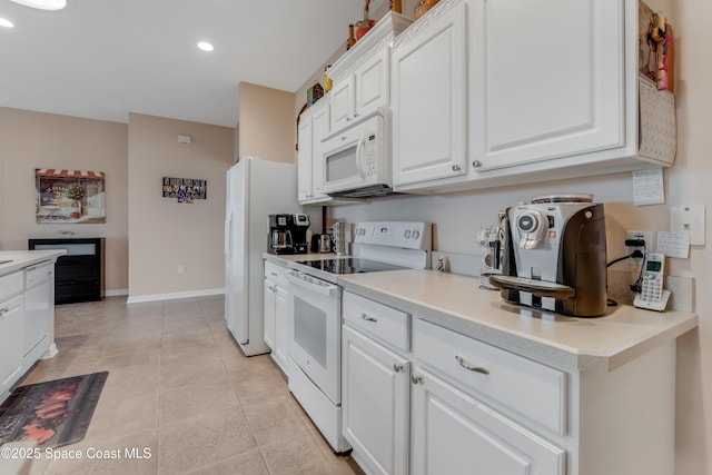 kitchen with light tile patterned flooring, white appliances, and white cabinets