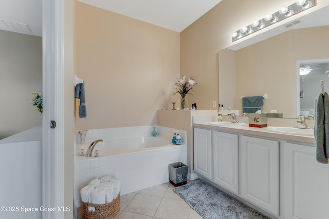 bathroom featuring tile patterned flooring, vanity, and tiled bath