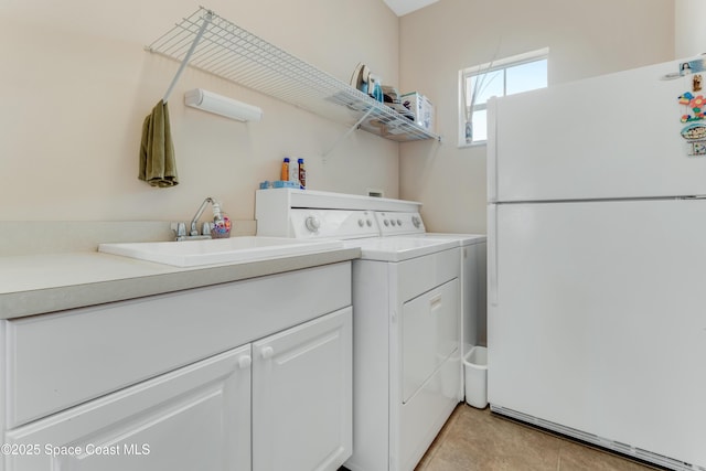 laundry room with light tile patterned flooring, washing machine and clothes dryer, and sink