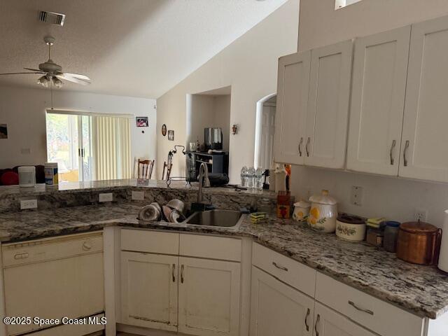 kitchen with lofted ceiling, sink, white dishwasher, light stone counters, and kitchen peninsula