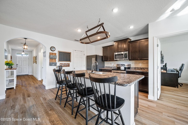 kitchen with a kitchen island with sink, sink, stainless steel appliances, and a kitchen breakfast bar