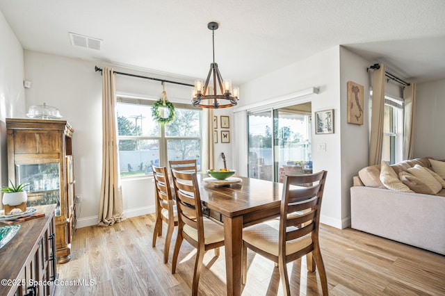 dining space featuring an inviting chandelier, a textured ceiling, and light wood-type flooring