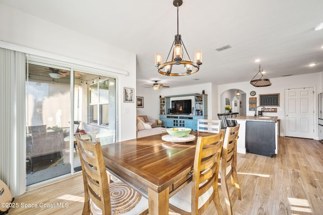 dining room featuring sink, ceiling fan with notable chandelier, and light wood-type flooring