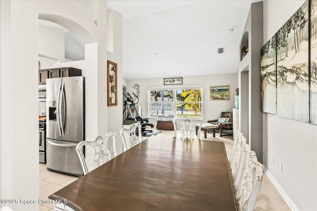 tiled dining area featuring vaulted ceiling