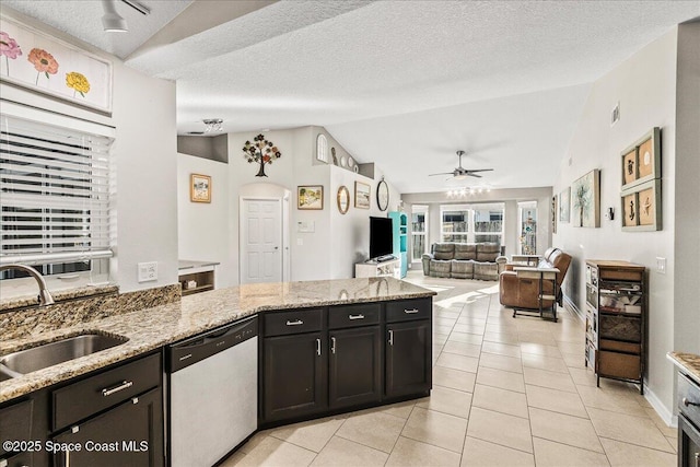 kitchen with sink, vaulted ceiling, light tile patterned floors, stainless steel dishwasher, and light stone countertops