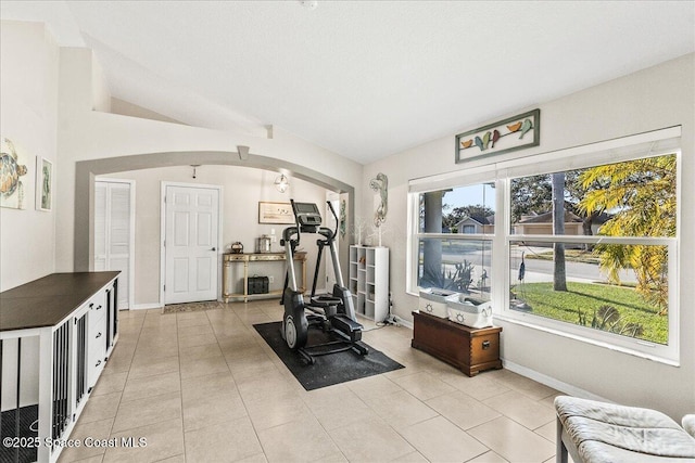 exercise area with light tile patterned floors and vaulted ceiling