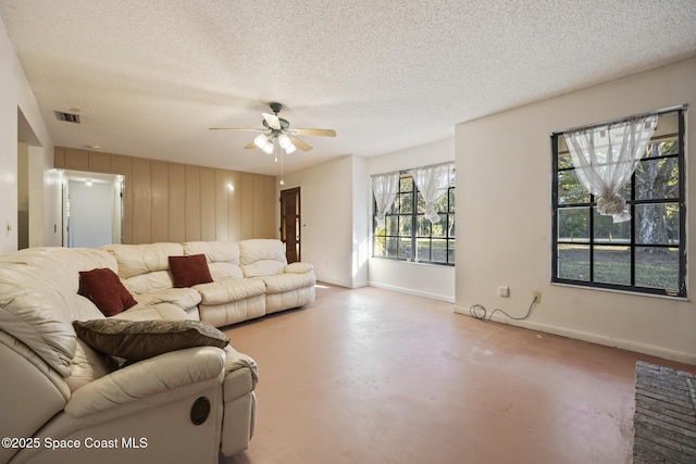 living room featuring ceiling fan and a textured ceiling