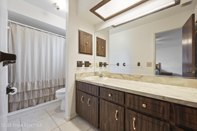 bathroom with tile patterned flooring, vanity, a skylight, and toilet