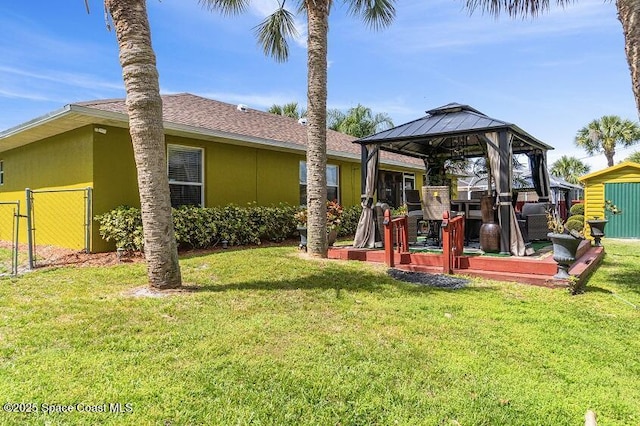 rear view of house featuring a gazebo and a lawn