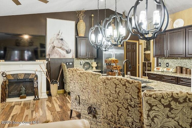 kitchen with lofted ceiling, dark brown cabinetry, and light hardwood / wood-style flooring