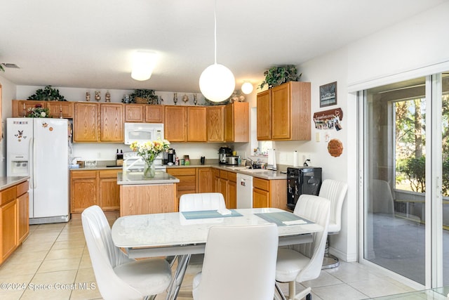 kitchen with a kitchen island, a breakfast bar area, hanging light fixtures, light tile patterned floors, and white appliances