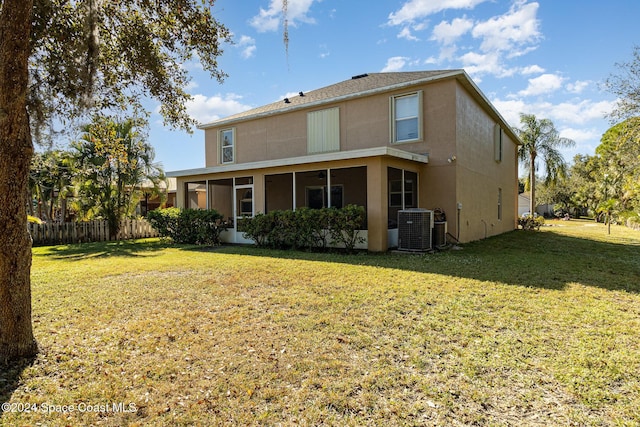 rear view of house with central AC unit, a yard, and a sunroom