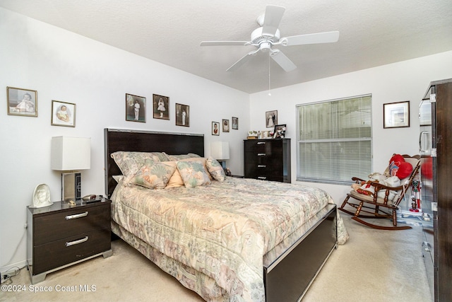 carpeted bedroom featuring ceiling fan and a textured ceiling