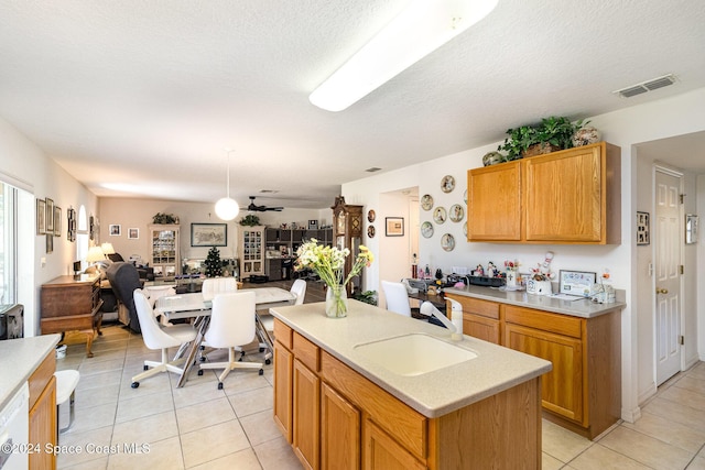 kitchen with light tile patterned flooring, sink, a kitchen island with sink, and a textured ceiling