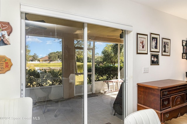 doorway to outside featuring tile patterned flooring, ceiling fan, and a water view