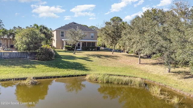 back of house with a water view and a yard