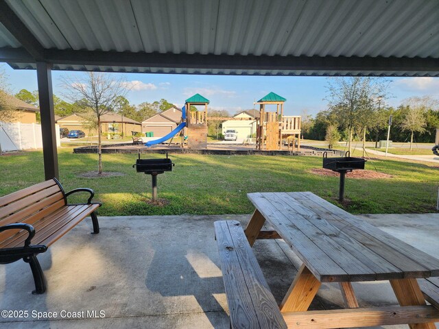 view of property's community with a playground, a lawn, and a patio area